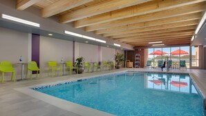 A swimming pool with wooden beams, bright green chairs, and tables. - Home2 Suites by Hilton Lewes Rehoboth Beach (Lewes)