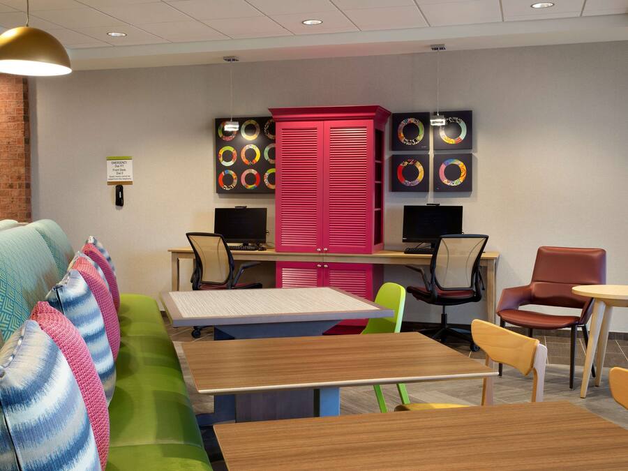 A modern meeting room with a green sofa, wooden tables, and colorful chairs.
