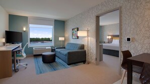 A hotel room with a desk, a sofa, a bed, and a dining area. - Home2 Suites by Hilton Lewes Rehoboth Beach (Lewes)