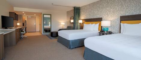 Ein Hotelzimmer mit zwei Betten, einem Schreibtisch, einem Fernseher und einem Badezimmer.