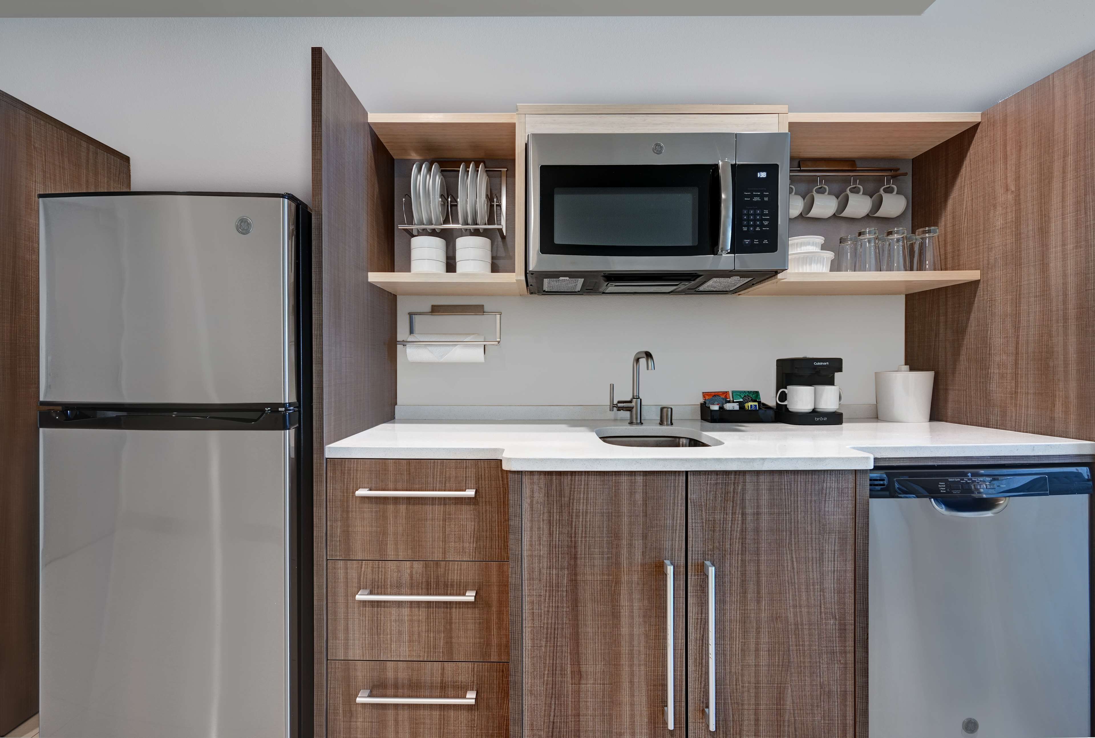 A modern kitchen with a stainless steel refrigerator, a built-in microwave, and a dishwasher.