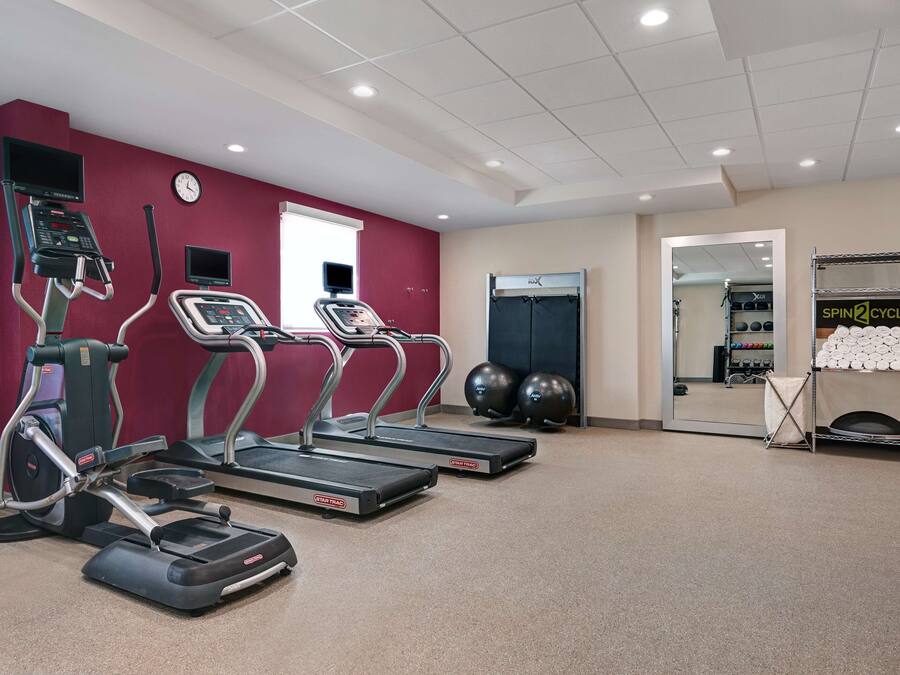 Un gimnasio con cintas de correr, elíptica y bicicleta estática.
