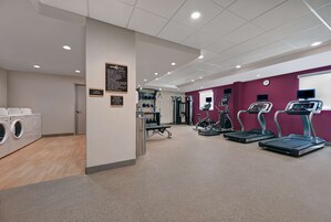 A gym with treadmills, weight machines, and a wall clock.