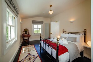 Un dormitorio con una cama grande, una mesita de noche, un espejo, un radiador y una ventana.
