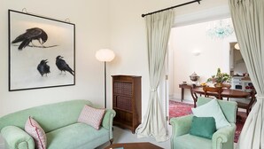 A living room with a green sofa, a wooden bookshelf, and a painting of birds. - Killadangan House (Westport)