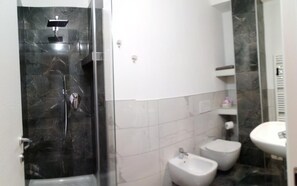 A bathroom with a glass-enclosed shower, two toilets, and a sink. - Casa della Zia Elsa (Verona)