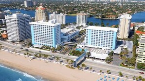 Un hotel costero con varios edificios altos, una playa y un puerto deportivo.