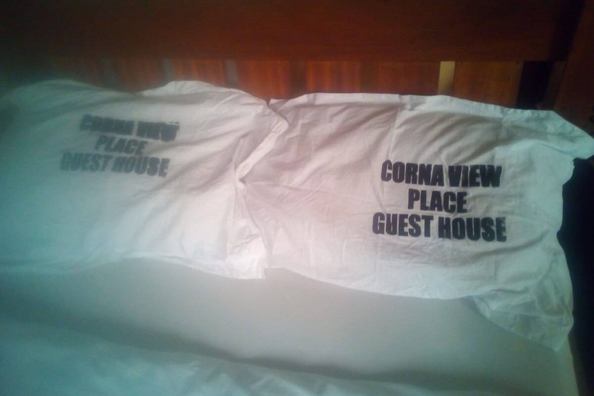 A bed with a pillow that reads "Cornava View Place Guest House".