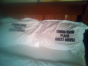 A bed with a pillow that reads "Cornava View Place Guest House".