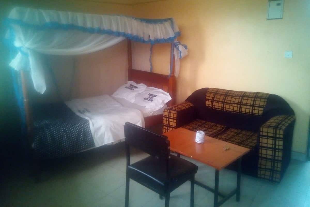 A single room with a bed, a sofa, a table, and a chair.