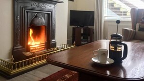 A cozy room with a fireplace, a coffee maker, and a television. - The Blue House (Westport)