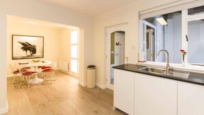 A modern kitchen with white cabinets, a black countertop, and a window. - The Blue House (Westport)