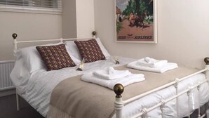 A neatly made bed with a patterned pillow, a folded towel, and a poster of Ireland on the wall. - The Blue House (Westport)