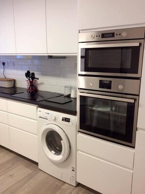 A kitchen with a washing machine, two ovens, and a countertop with a knife holder. - The Blue House (Westport)