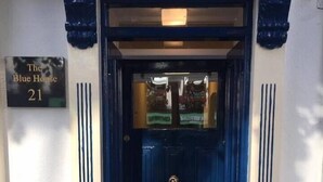 A blue door with a brass handle and a sign above it that reads "The Blue House 21". - The Blue House (Westport)