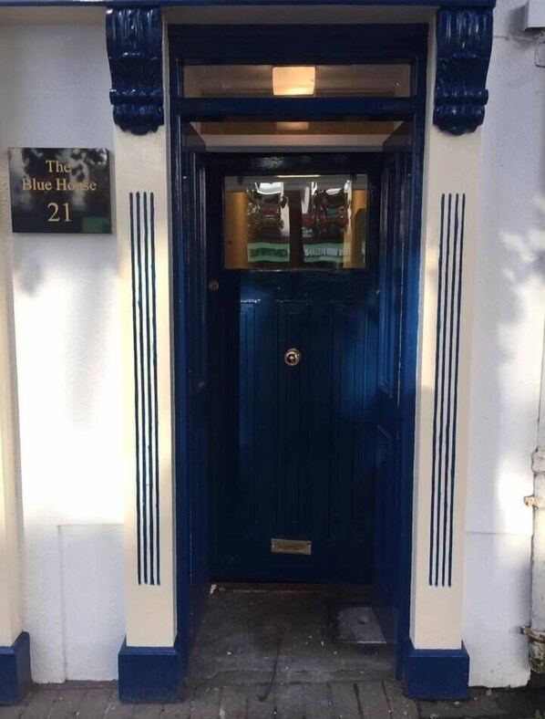 A blue door with a brass handle and a sign above it that reads "The Blue House 21". - The Blue House (Westport)