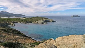 A coastal landscape with rocky terrain, clear blue waters, and distant mountains. - CAPO BIANCO - Cap Corse et Vue Mer (Ersa)