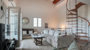 A spacious living room with a sofa, a coffee table, and a spiral staircase.