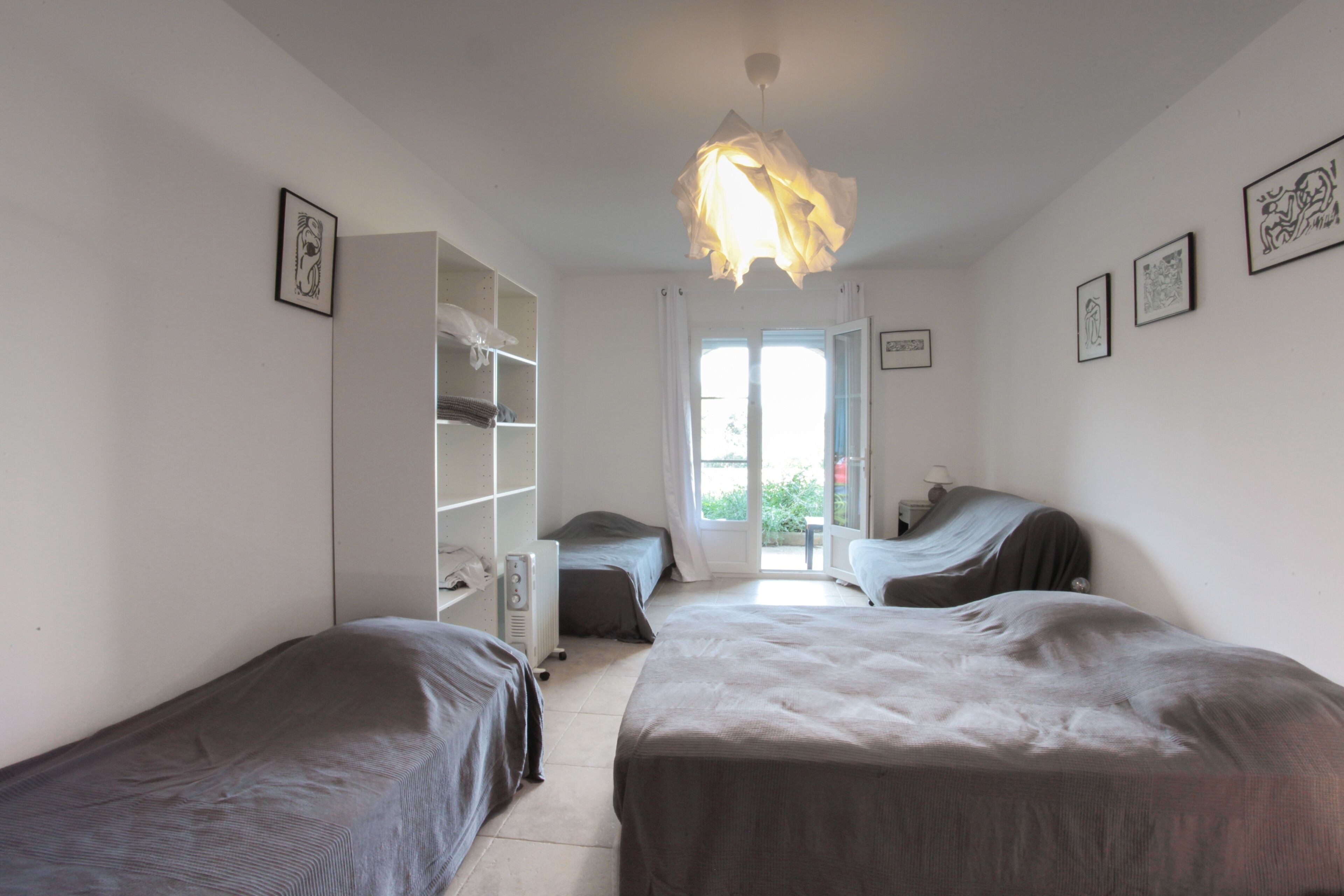 A room with two beds, a wardrobe, and a door leading outside.