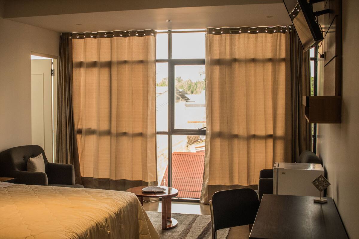 Ein Hotelzimmer mit einem Bett, einem Schreibtisch, einem Stuhl und einem kleinen Tisch.