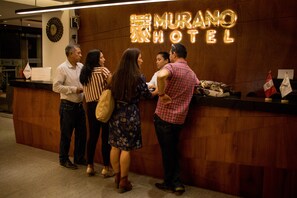 A reception desk at the Murano Hotel with a wooden facade and a neon sign. - Murano Hotel (Moyobamba)