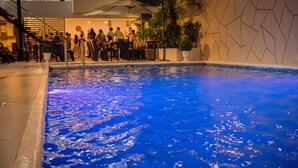 An indoor pool with a blue reflective surface, surrounded by seating areas and a staircase. - Murano Hotel (Moyobamba)