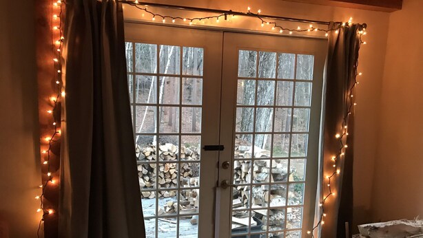A room with a wooden floor, a door with glass panels, and a view of a forest through the door. - Cozy cottage tucked away in the woods (Townshend)