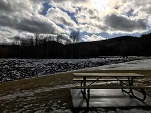 Uma mesa de piquenique num parque com neve no chão e árvores ao fundo.