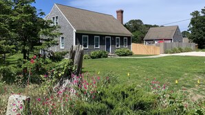 A residential house with a sloped roof, a chimney, and a well-maintained lawn. - Pristine home w/heated saltwater pool, just minutes from beaches and bike trail. (Eastham)