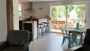 A modern kitchen with a central island, bar stools, and a dining area with a table and chairs. - Pristine home w/heated saltwater pool, just minutes from beaches and bike trail. (Eastham)