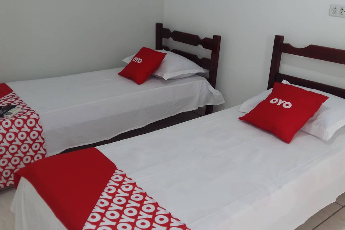 Two single beds with wooden headboards, white bedding, and red pillows with 'oyo' text.