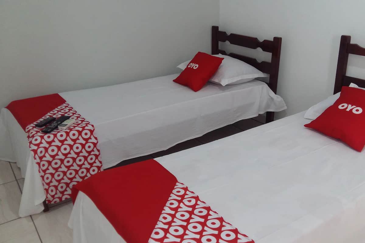 Two single beds with wooden headboards, white bedding, and red accents.