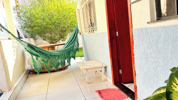 A tiled patio with a hammock, a small table, and a red door. - OYO Pousada Paraná, Cuiabá (Cuiabá)