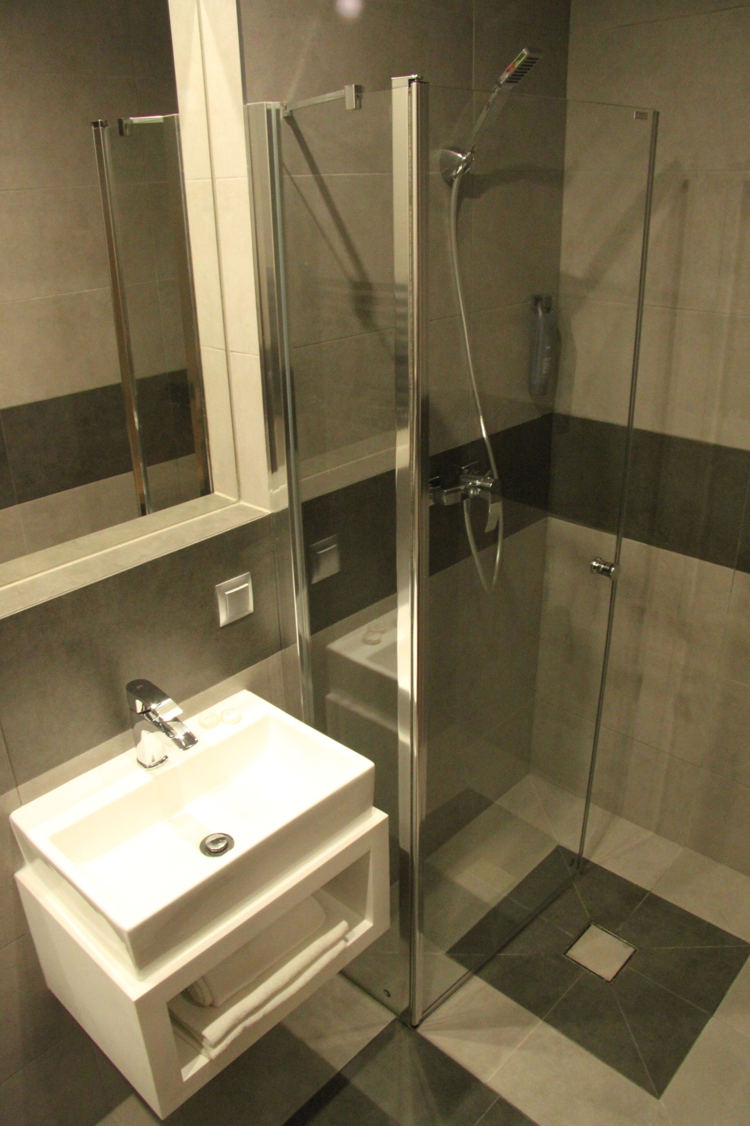 A modern bathroom with a glass-enclosed shower, a white sink, and a mirror above the sink.