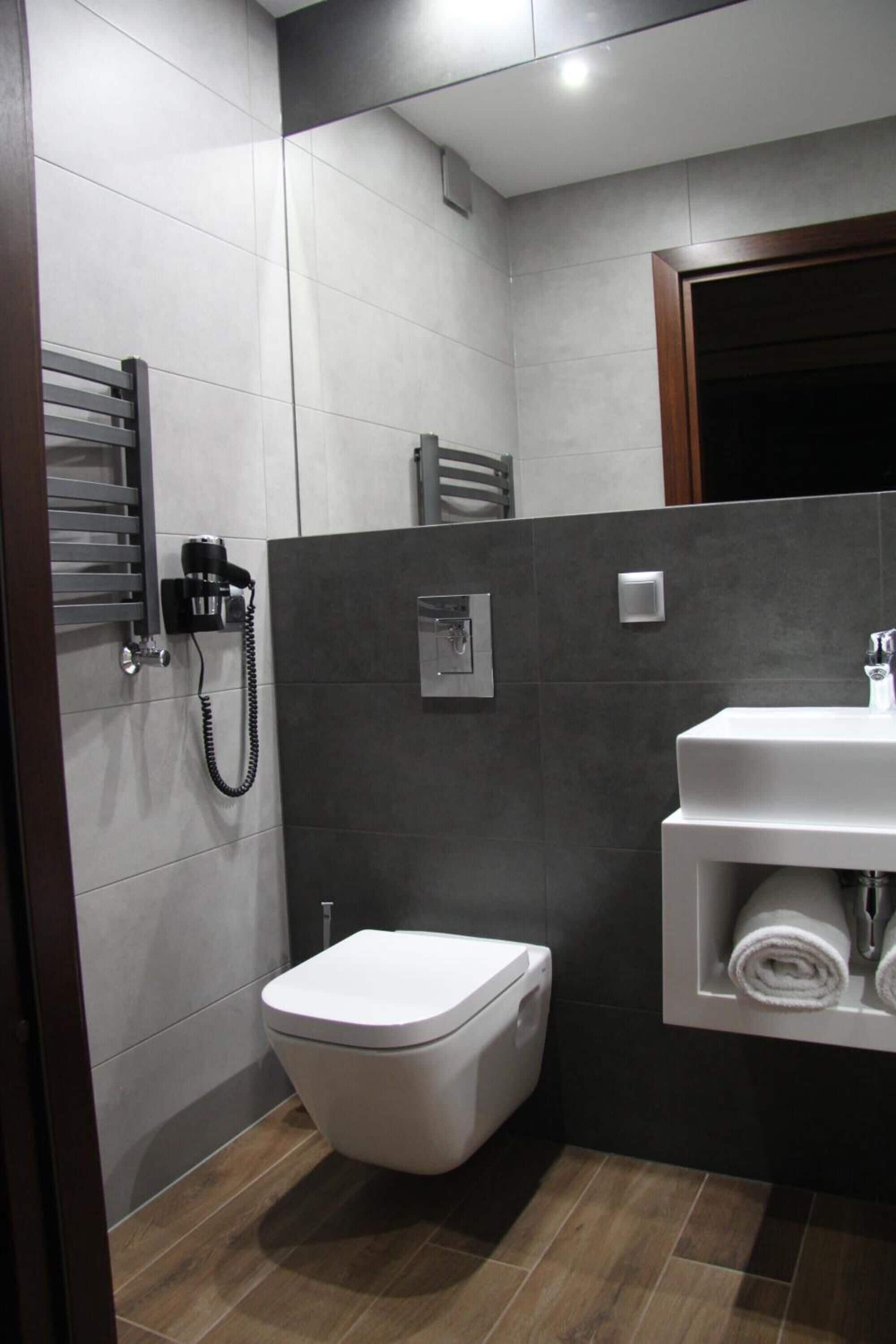 A modern bathroom with a toilet, a sink, and a towel rack.