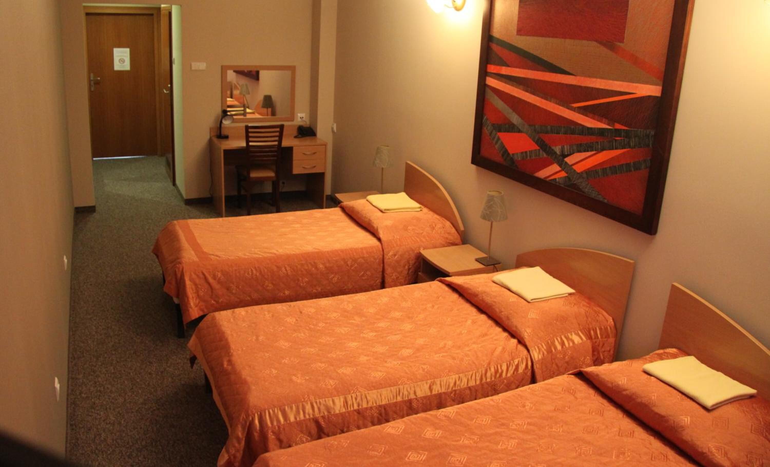 Habitación de hotel con tres camas, un escritorio y una silla.