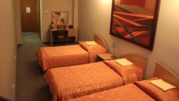 Habitación de hotel con tres camas, un escritorio y una silla.