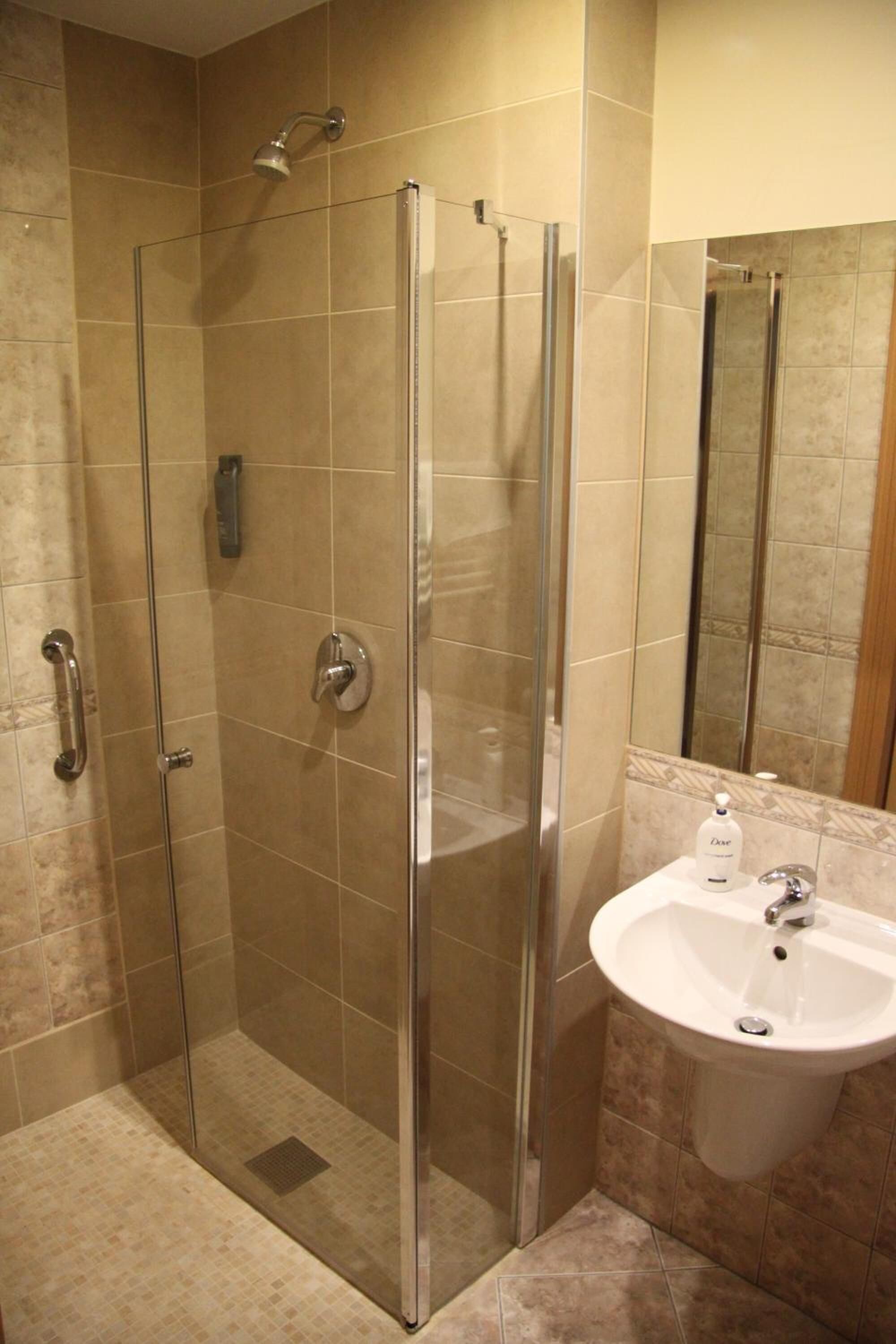 A modern bathroom with a glass-enclosed shower, a white sink, and a mirror.
