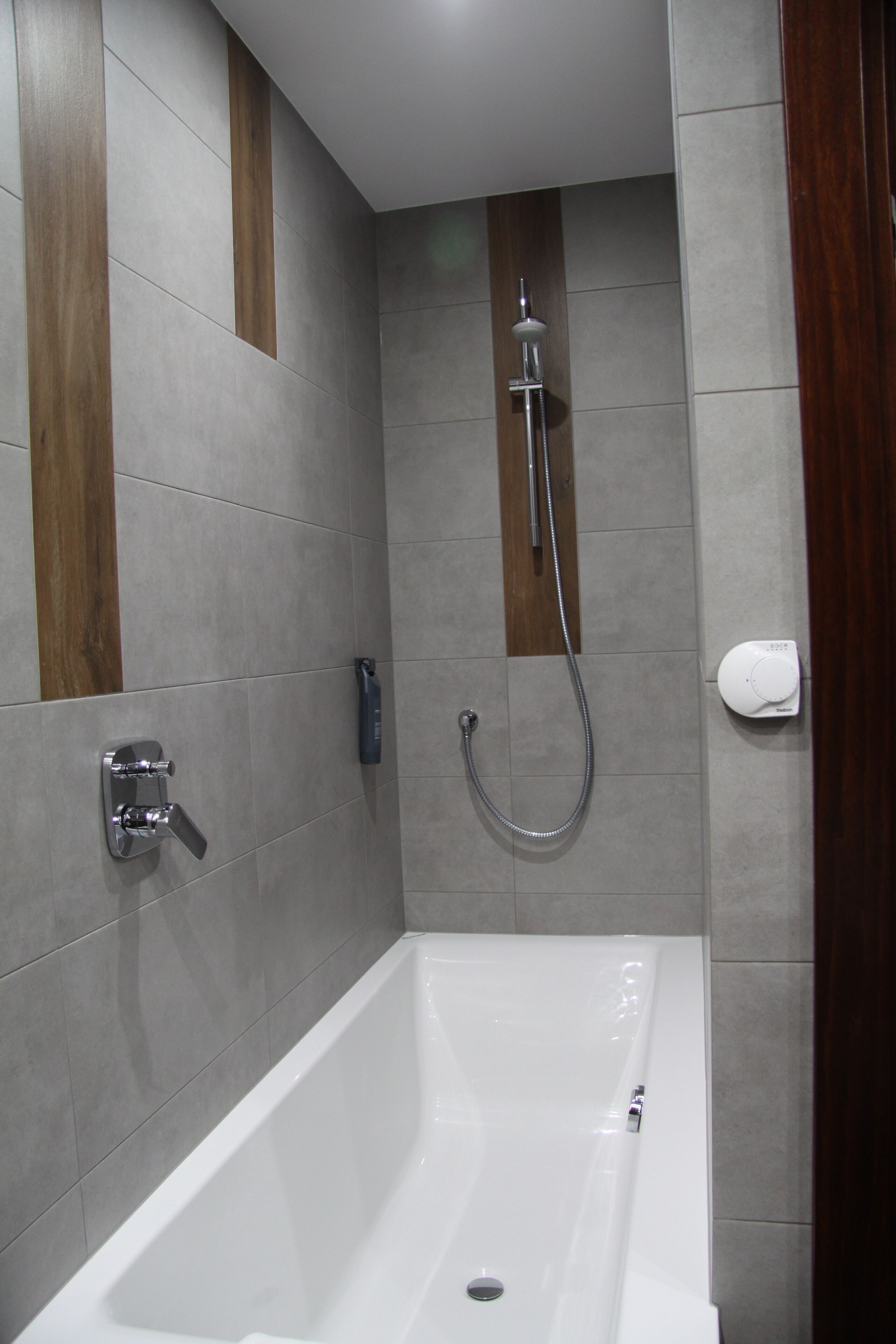 A modern bathroom with a bathtub, a handheld showerhead, and a wall-mounted toilet.