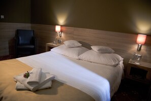 A hotel room with a large bed, two bedside tables, a chair, and wall-mounted lamps. - Hotel Dunajec (Tarnow)