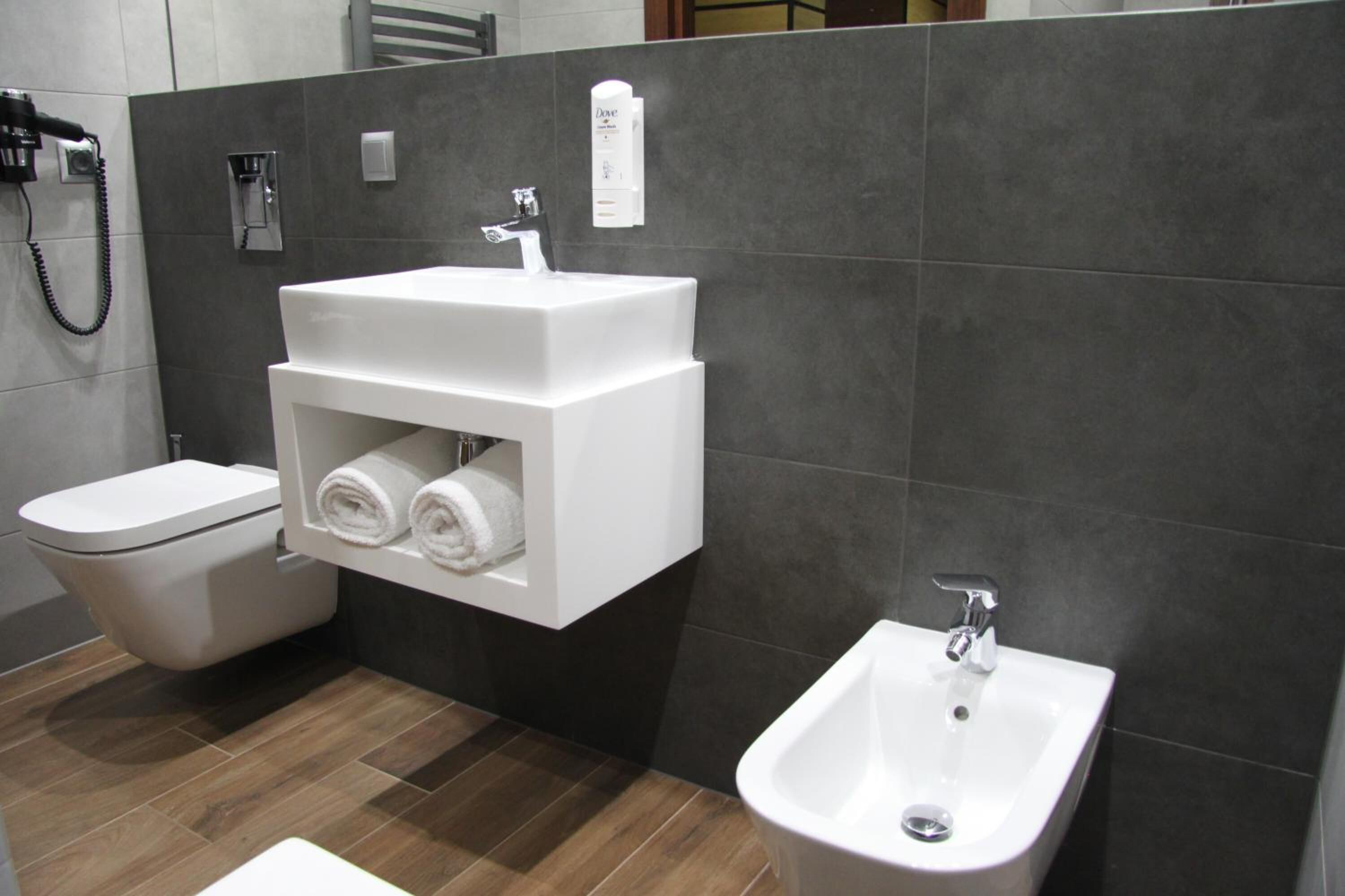 A modern bathroom with a toilet, a sink with a towel rack, and a bidet.