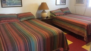 A room with two beds, each with striped bedding, a bedside lamp, and framed pictures on the walls. - Lakefront Suite - 12 (Kingsland)