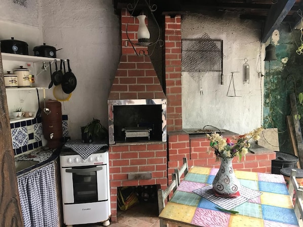 A kitchen with a brick oven, a stove, and a table with a colorful tablecloth.