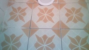Un inodoro con asiento blanco y piso estampado.