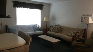 Una sala de estar con sofá, sillón, mesa de centro y una mesa de comedor con sillas.