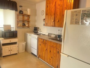 Una cucina compatta con microonde, macchina del caffè, lavastoviglie e mobili in legno.