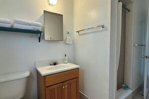Ein Badezimmer mit Waschbecken, Spiegel, Handtuchhalter und Dusche.