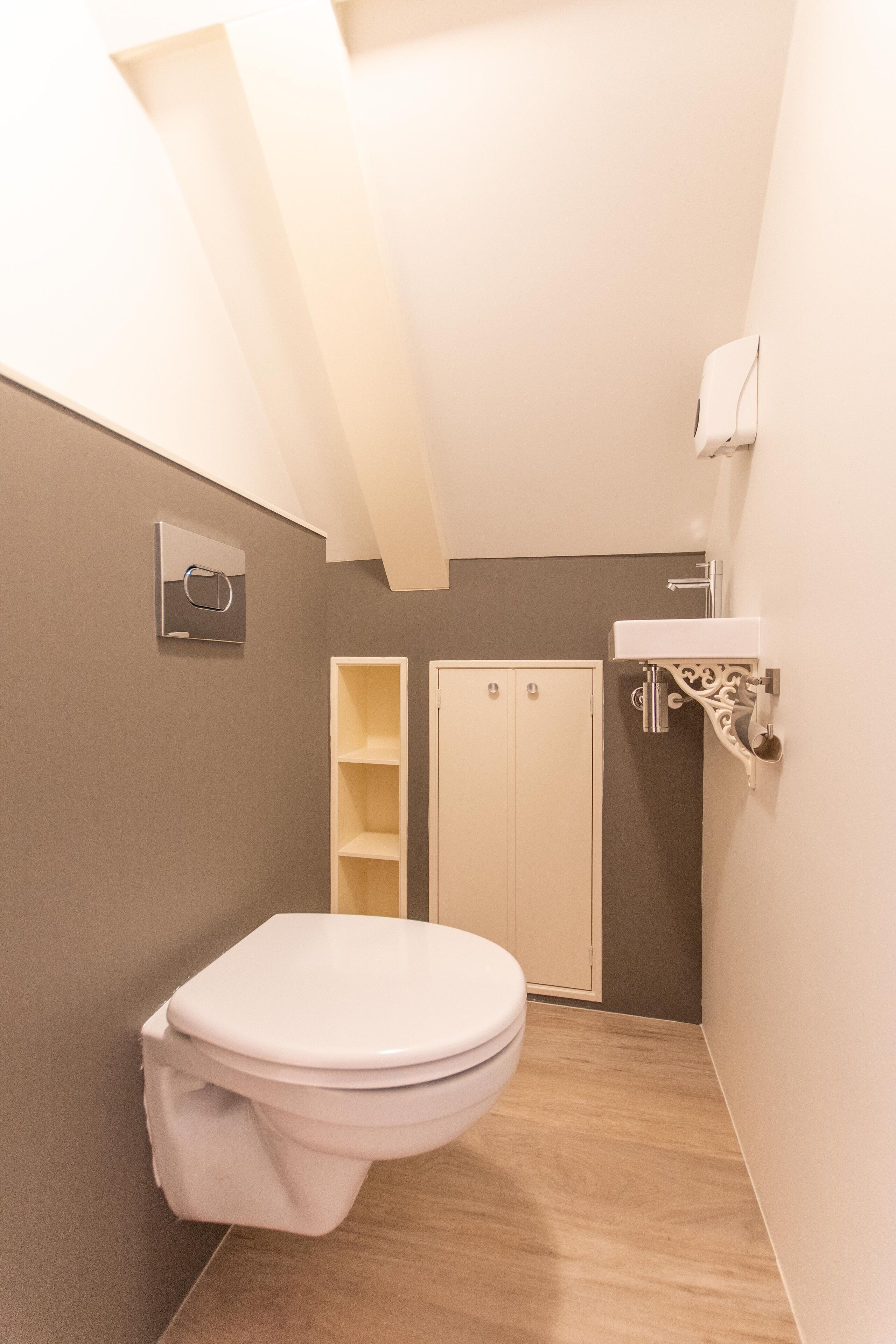 A small, narrow bathroom with a toilet, a sink, and a shower area.