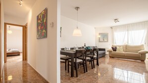 Ein geräumiges Wohnzimmer mit Essbereich, einer Couch und einem Bett im Hintergrund.