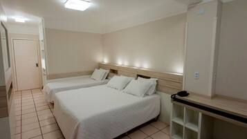A hotel room with two beds, a desk, and a chair.